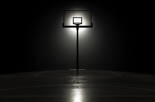A concept showing hoop on a reflective concrete lined basketball court backlit by a single honeycomb spotlight - 3D render