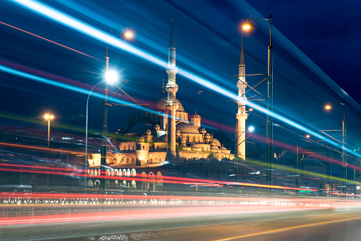 Night shot of Galata Bridgew with traffic and illuminated Yeni Cami mosque in back.