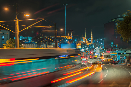 Shot of Galata Bridgew with traffic and illuminated Yeni Cami mosque in back.