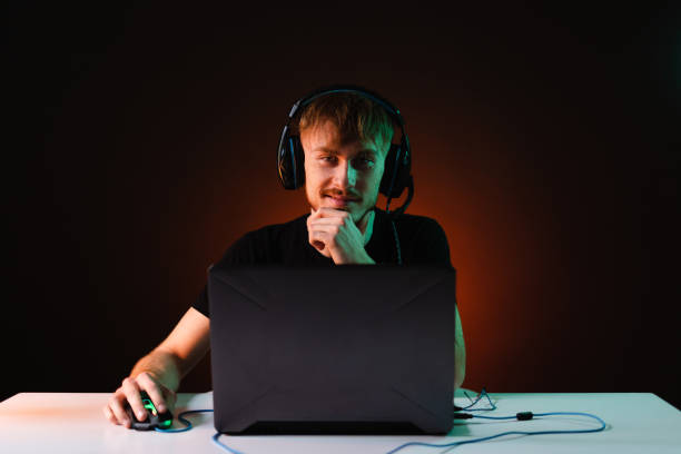 Gamer playing video games with headphones on neon light background stock photo