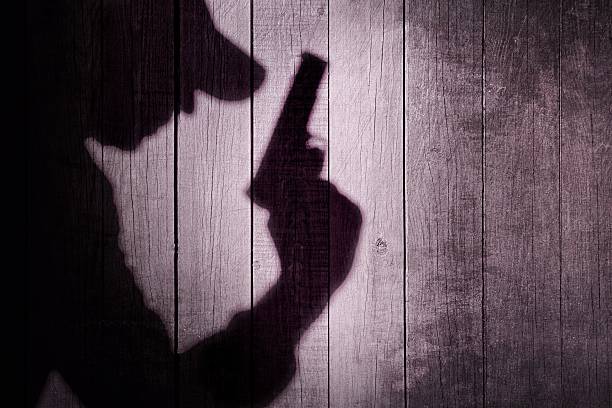 Gangster or investigator or spy silhouette on natural wooden wal Gangster or investigator or spy silhouette on natural wooden wall. You can see more silhouettes and shadows on my page. murder stock pictures, royalty-free photos & images