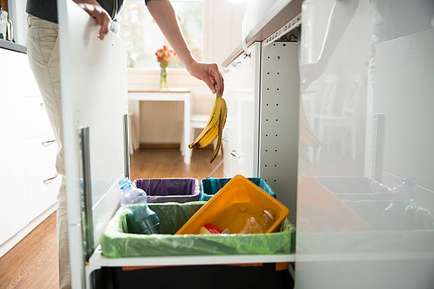 Garbage cans. Recycling concept. Woman putting banana peel in recycling bio bin in the kitchen cabinet. Person in the house separating waste. Different trash can with colorful garbage bags. garbage photos stock pictures, royalty-free photos & images