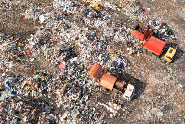 Garbage truck unloads rubbish in landfill. Landfill waste disposal. Garbage dump with waste plastic and polyethylene. stock photo