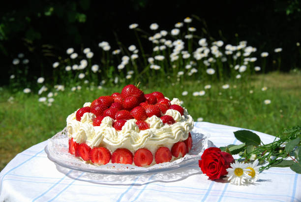 Garden table with a strawberry cake and summer flowers stock photo