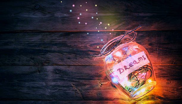 garlands of colored lights in glass jar with dreams garlands colorful lights in glass jar with dreams, sparks, on old wooden table, retro toned dreaming stock pictures, royalty-free photos & images