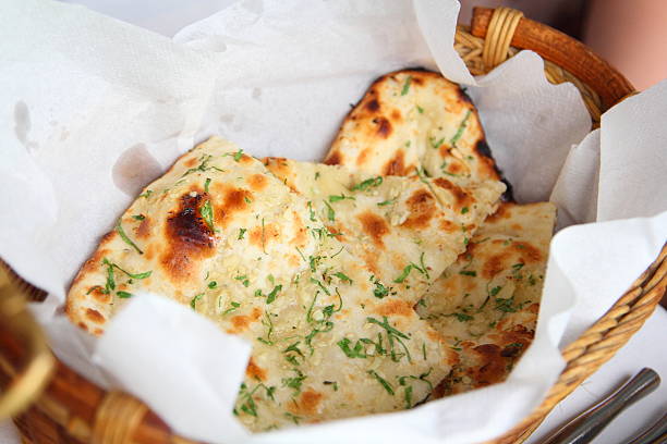 Garlic Naan Indian Flatbread Two pieces of garlic naan bread in a basket. naan bread stock pictures, royalty-free photos & images