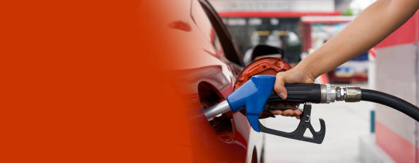 Gas station worker's hand holding blue benzene gas pump, filling up orange sport car tank. Close up stock photo