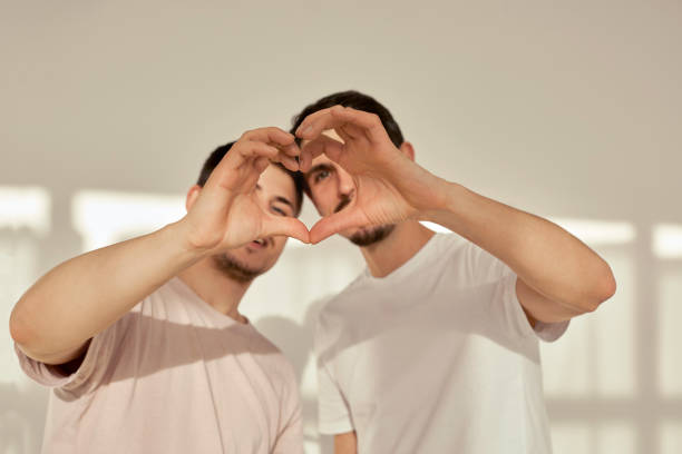 Gay couple of men make heart shape out of hands stock photo