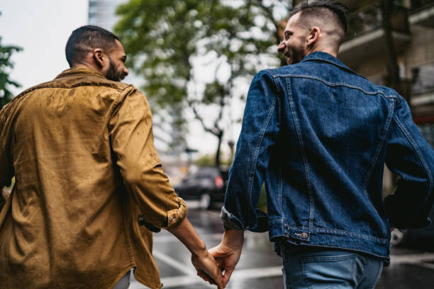 Gay couple walking in the rain holding hands stock photo