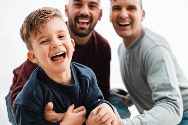Gay male parents having fun with their son outdoor - Focus on kid boy face stock photo