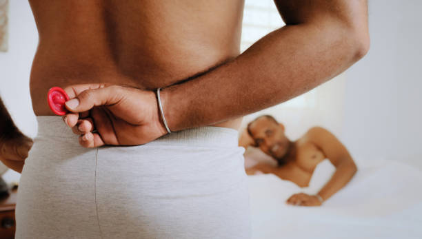 Gay People Using Condom For Safe Sex In Home Bed"n stock photo