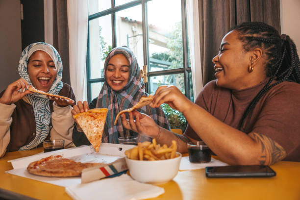 Gen Z friends dining together with pizza and fries stock photo
