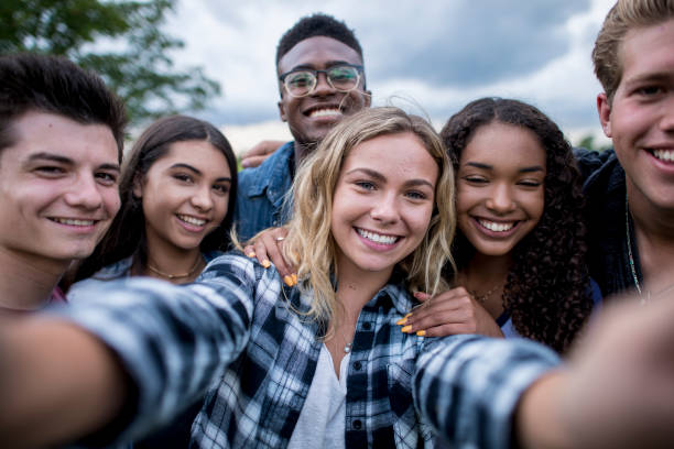 Generation Z A multi-ethnic group of teenagers are outdoors on a cloudy day. They are wearing casual clothing. They are smiling while taking a selfie together. generation z stock pictures, royalty-free photos & images
