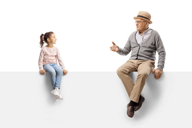 Gentleman sitting on a blank panel and talking to a child stock photo