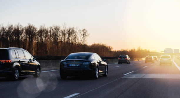 German autobahn with multiple cars driving Offenburg: Tesla P85 and Multiple cars driving on the winter evening on the German Autobahn with the direction Offenburg, Basel, Frankfurt with beautiful sunset and sun flare audi photos stock pictures, royalty-free photos & images