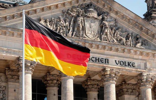 Germany Politics Concept: German Flag In Front of The Reichstag Building Germany Politics Concept: German Flag In Front of The Reichstag Building In Berlin, Germany With Dedication Dem Deutschen Volke, Meaning To The German People chancellor stock pictures, royalty-free photos & images