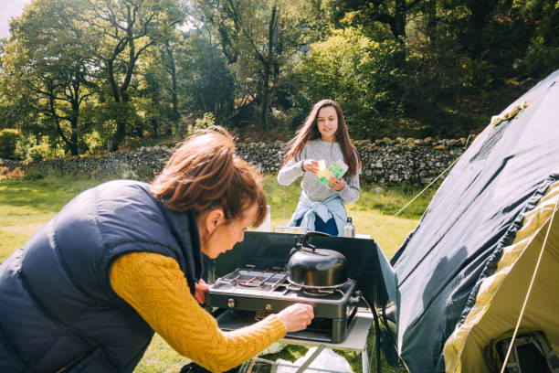 Getting Ready for Breakfast at the Tent Mature woman is trying to put the gas stove on to make herself and her granddaughter a cup of tea. camping stove stock pictures, royalty-free photos & images