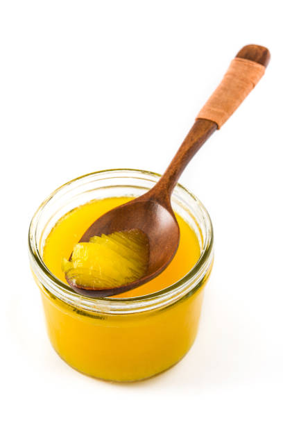 Ghee or clarified butter in jar Ghee or clarified butter in jar and wooden spoon isolated on white background ghee stock pictures, royalty-free photos & images