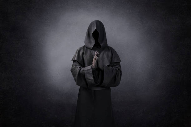 Ghostly figure praying in the dark stock photo