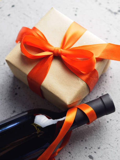 A gift box with a red ribbon and a bottle of wine on the table. The concept of Valentine's day, birthday or anniversary A gift box with a red ribbon and a bottle of wine on the table. The concept of Valentine's day, birthday or anniversary happy birthday wine bottle stock pictures, royalty-free photos & images
