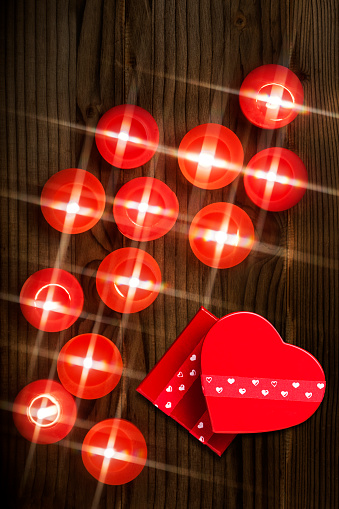 Gift Boxes and red Tealights on brown wooden background.