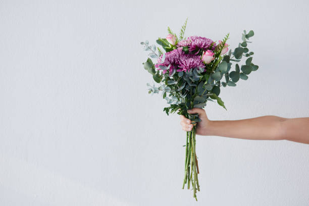Gifts from Mother Nature's garden Studio shot of an unrecognizable woman holding a bunch of flowers against a grey background bouquet stock pictures, royalty-free photos & images