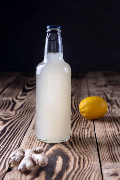 бутылка имбирного пива с лимоном на деревянном фоне - эль стоковые фото и изображения