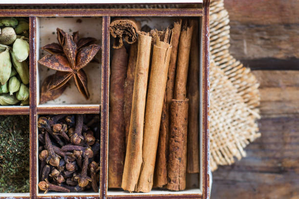 ginger, mint, clove, chili flakes, cardamon, star anise, cinnamo Box with variety of dried spices, such as ginger, mint, clove, chili flakes, cardamon, star anise, cinnamon sticks on dark rustic wooden background spices of the world stock pictures, royalty-free photos & images