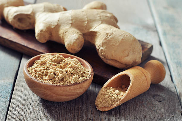 Ginger root and powder on a wooden table stock photo