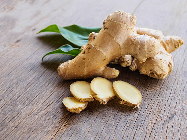 Ginger root slice with leaf and has a spicy taste Ginger root slice with leaf and has a spicy taste on wooden background ginger spice stock pictures, royalty-free photos & images