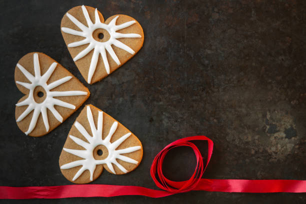 Gingerbread heart shaped cookies with icing and red ribbon on dark background stock photo