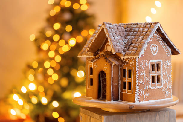 gingerbread house over defocused lights of Chrismtas decorated fir tree stock photo