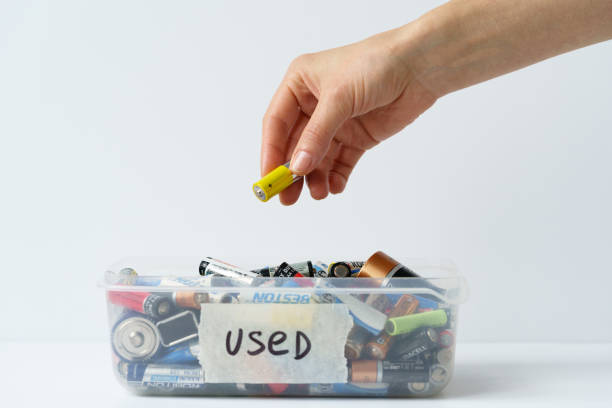 Oslo, Norway - April 15, 2021. Girl arm putting used discharged battery in plastic container. stock photo
