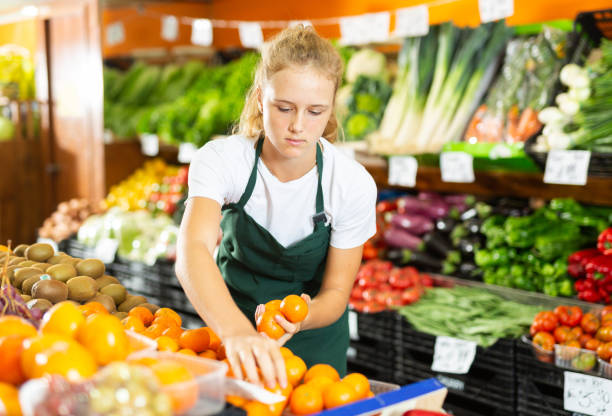 Girl at her first job in vegetable shop stock photo