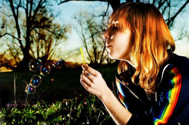 Girl Blowing Bubbles and Sitting Outside stock photo
