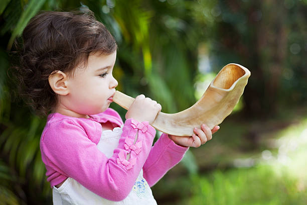A little girl blows a shofar for Rosh Hashana, the Jewish New Year.