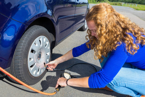 Girl checking air pressure of car tire stock photo