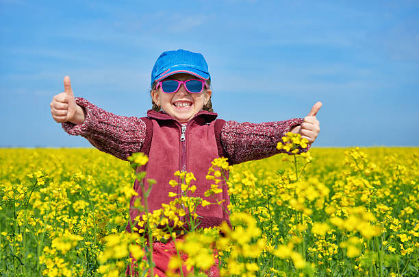 girl child in rapeseed field with bright yellow flowers stock photo
