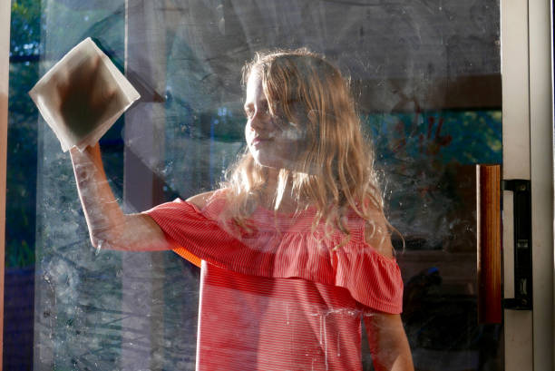 Girl cleaning a dirty window stock photo