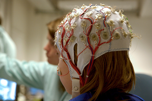 for a scientific experiment, a girl is connected with cables to a computer, EEG for research,