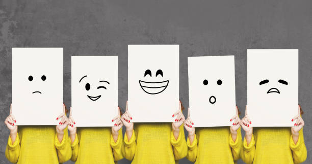 Girl covering face with white boards. Set of painted emotions Emotions set. Girl hiding face behind signboard with drawn smileys. Collage of indifferent, winking, happy, surprised, and sad emoticons. facial expression photos stock pictures, royalty-free photos & images