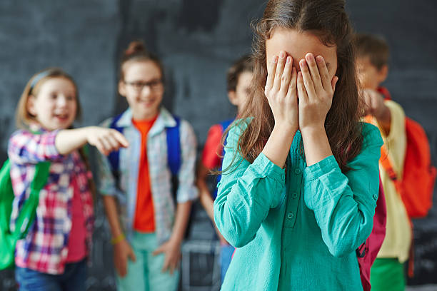 Girl crying Schoolgirl crying on background of classmates teasing her bullying stock pictures, royalty-free photos & images