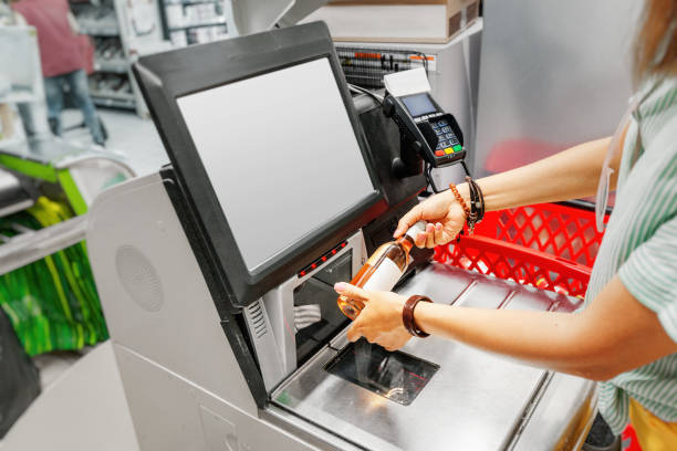 Girl customer scans bottle of wine at the self-service checkout in the grocery supermarket shop Girl customer scans bottle of wine at the self-service checkout in the grocery supermarket shop self service photos stock pictures, royalty-free photos & images