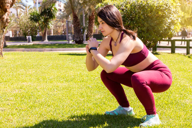 A girl doing squats in a park stock photo
