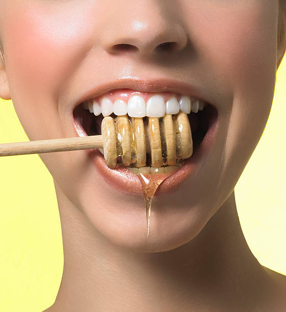 Girl eating fresh honey with wide open mouth stock photo