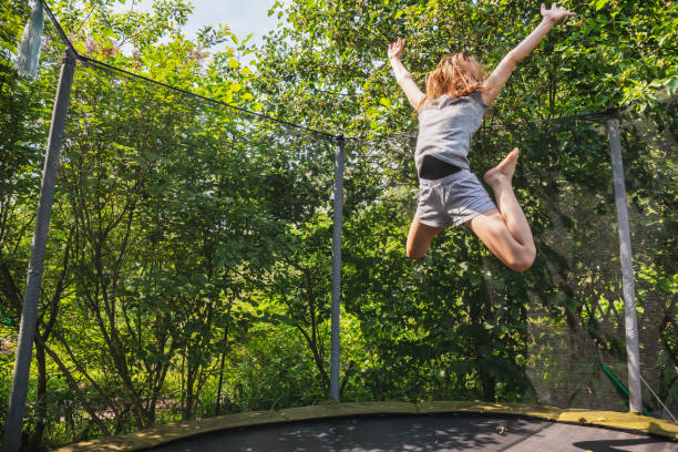 Girl enjoy bouncing on a trampoline outdoors stock photo