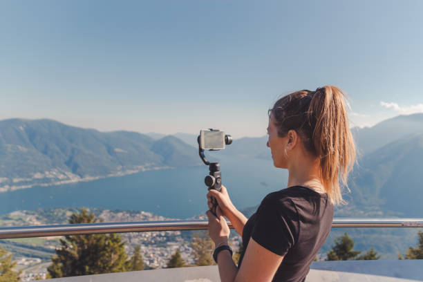 girl filming with gimbal in the mountains over lake maggiore - smartphone filming imagens e fotografias de stock