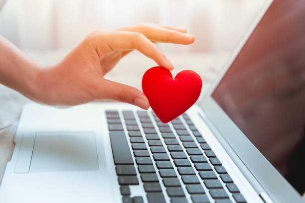 de hand van het meisje neemt rood hart bij laptoptoetsenbord voor sociale online liefdepraatje en het delen van aanmoediging over internet om covid-19 virus samen te bestrijden. - romantiek begrippen stockfoto's en -beelden