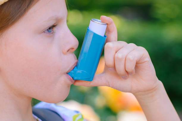 Girl having asthma using asthma inhaler for being healthy - shallow depth of field stock photo