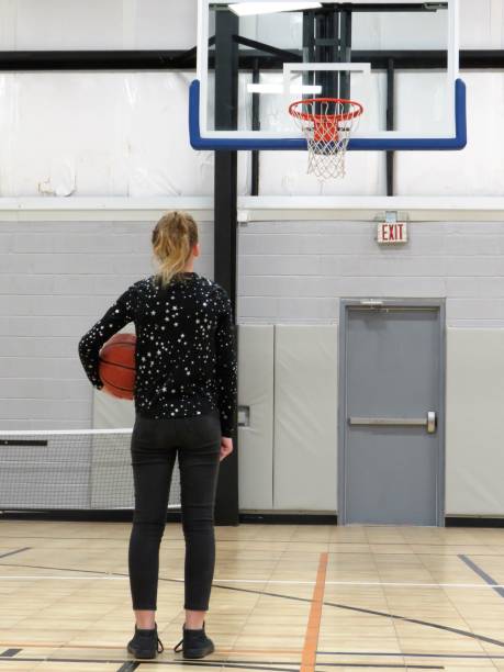 meisje holding basketbal staande voor basketbal net op het hof - basketball player back stockfoto's en -beelden